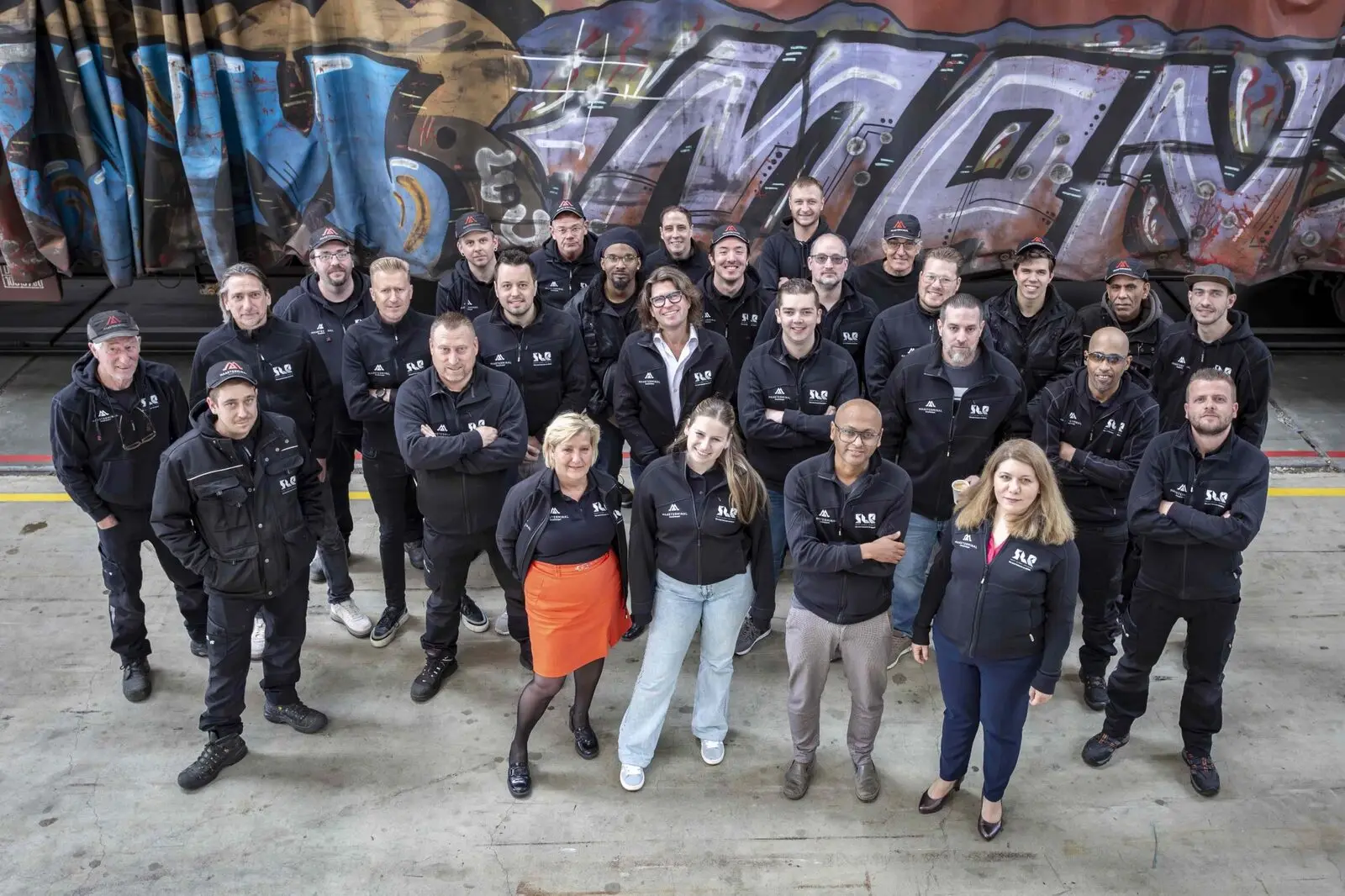 The Maasterminal and SLE team, around thirty people, in front of a graffiti-covered rail wagon