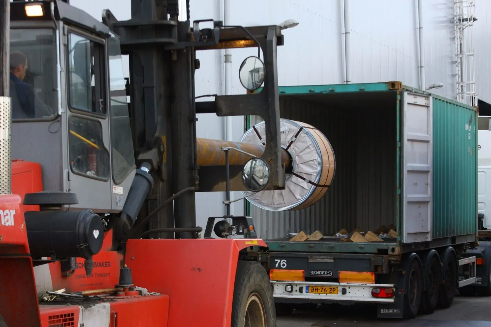 Reach truck loading a steel coil into a shipping container